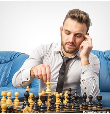عکس مرد جوان متفکر در حال بازی شطرنج با خودش در منزل در کنار مبل آبی