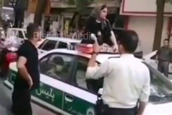 ببینید | نشستن یک زن روی ماشین پلیس برای آزادی شوهرش!