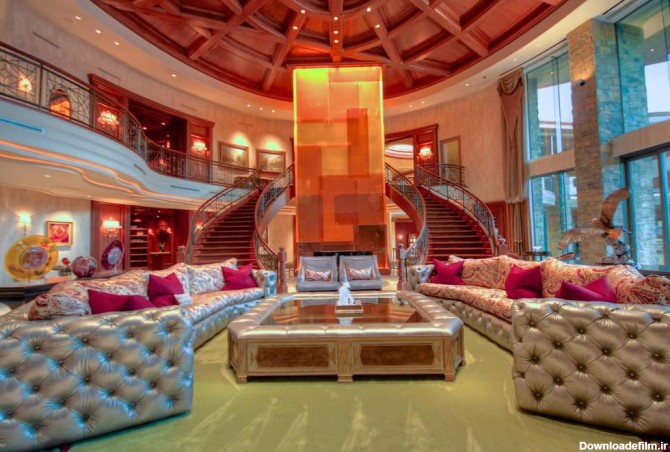 نشیمن بزرگ خانه دوبلکس لوکسی که با مبل های طوسی چسترفیلد، کوسن های سرخابی و میز جلو مبلی طوسی دکور شده است