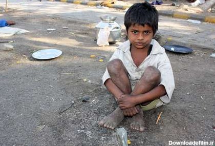 يک بچه فقير در هند، نشسته در خيابان.