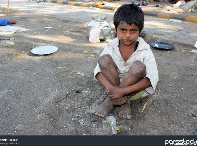 یک بچه فقیر در هند کنار خیابان نشسته است 1206468