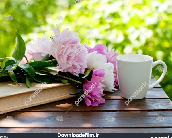 کتاب گل و یک فنجان چای روی یک میز در یک باغ بهاری کارت یا تقویم ...