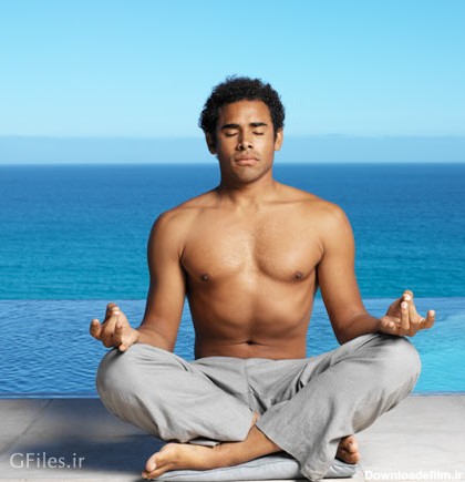 دانلود تمرین یوگا در کنار دریا توسط مرد جوان بدون پیراهن با چشمان بسته به حالت چهارزانو