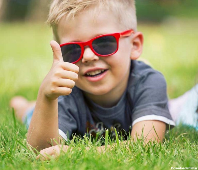دانلود تصویر با کیفیت پسر بچه با عینک آفتابی در حال نشان دادن علامت لایک
