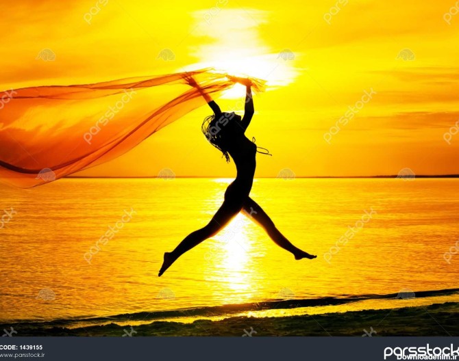 شبح دختر جوان پریدن با پارچه ابریشم در برابر غروب خورشید 1439155