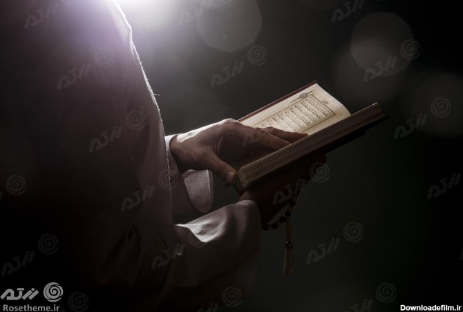 عکس با کیفیت از مرد درحال خواندن قرآن از نمای کنار در تاریکی | رزتم