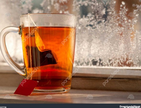 یک کیسه چای در یک لیوان یک لیوان چای بر روی پنجره بالکن در زمستان ...
