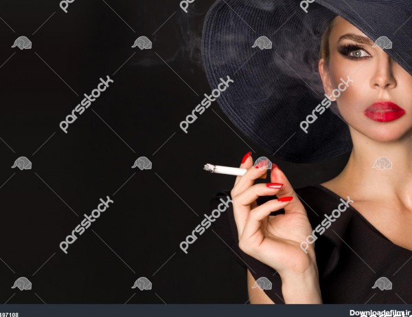 زن زیبا زنانه female در کلاه سیاه با سیگار در دست روی زمینه سیاه ...