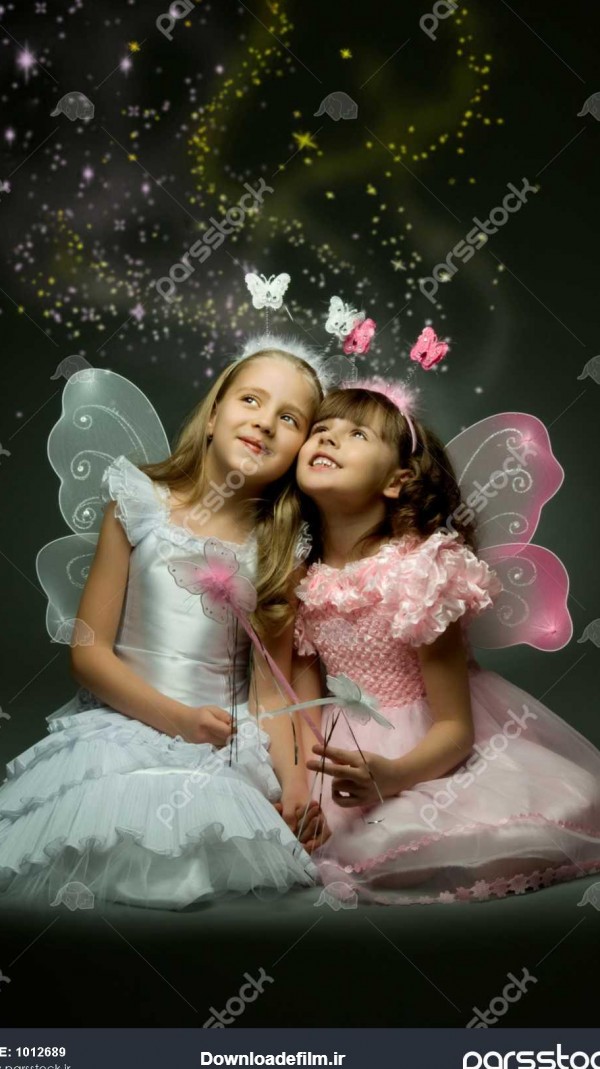 دو دختر بچه زیبا با بال ، نشسته و لبخند در پس زمینه تاریک 1012689