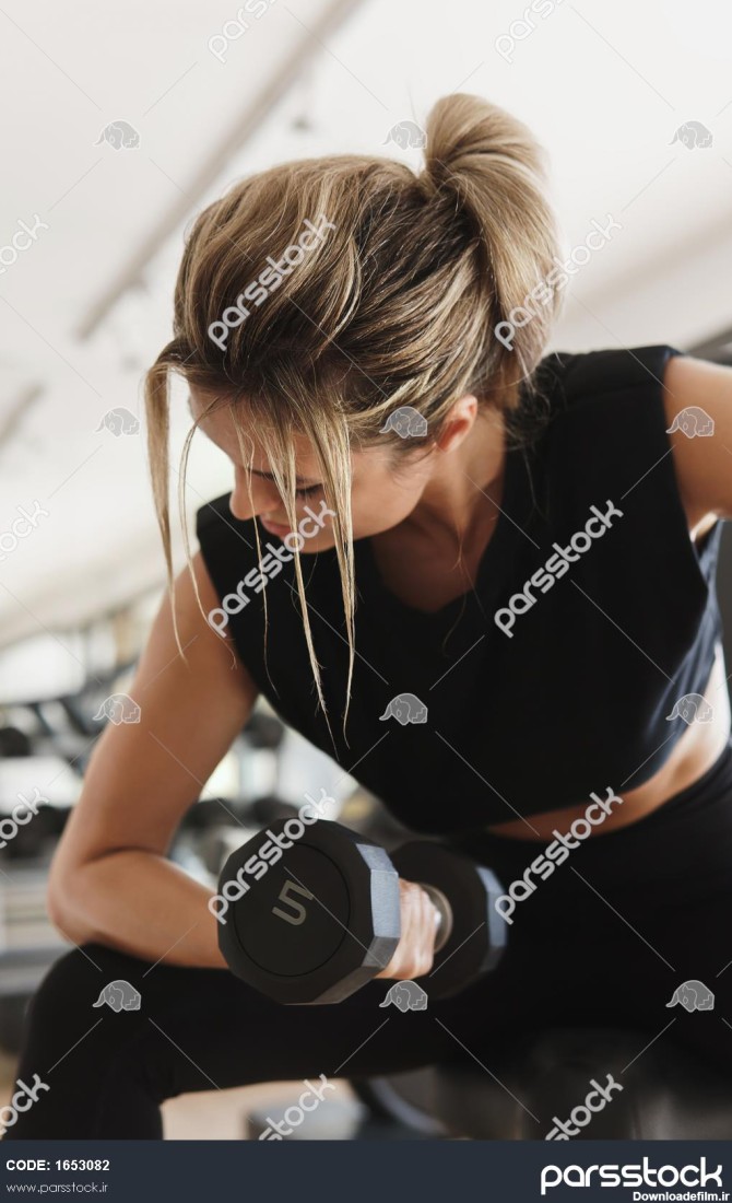 زن جوان ورزشکار در حال انجام تمرین حلقه دو سر بازو با دمبل در ...