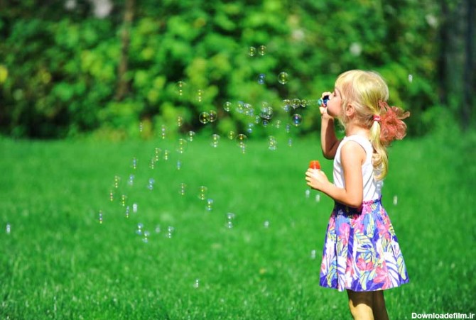 دانلود تصویر با کیفیت دختر بچه در فضای باز در حال حباب زدن