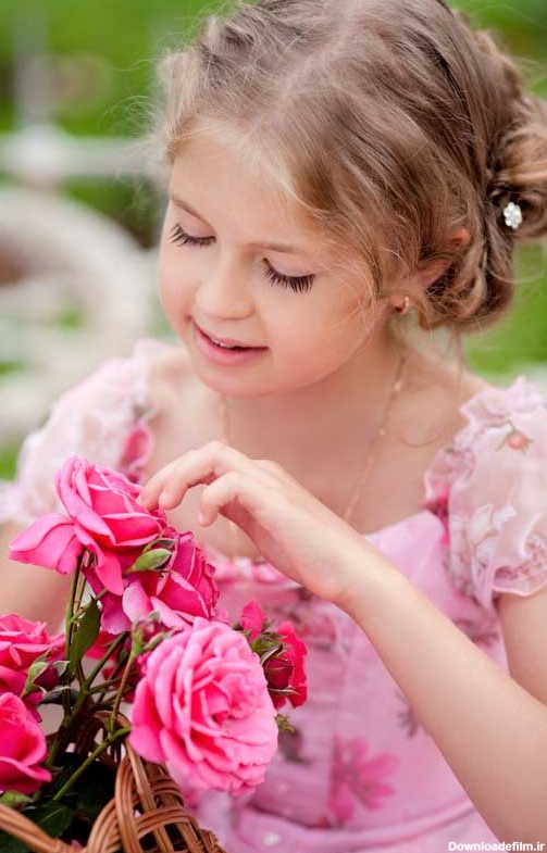 دانلود تصویر با کیفیت دختر بچه در حال نگاه کردن به گل