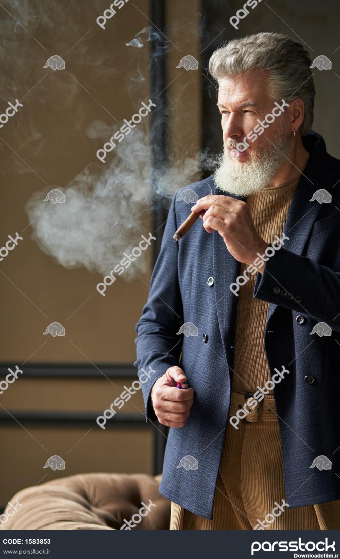 مرد میانسال وحشی شیک با ریش و در حالی که سیگار می کشد در اتاق زیر ...
