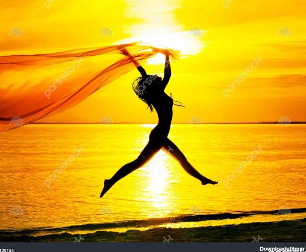 شبح دختر جوان پریدن با پارچه ابریشم در برابر غروب خورشید 1439155