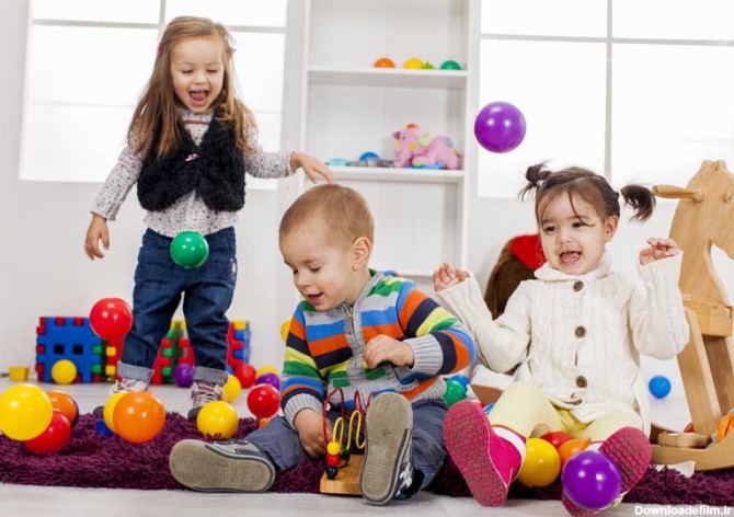 دانلود تصویر با کیفیت سه کودک خوشحال در حال بازی کردن با توپ های رنگی