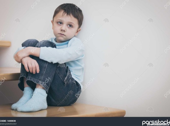 یک پسر کوچک غمگین که در روز در کنار ساحل نشسته است مفهوم غم و ...