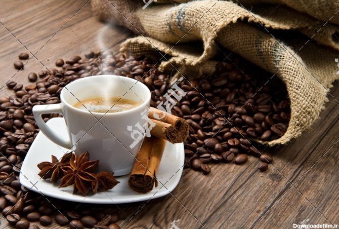 عکس دانه های قهوه و فنجان قهوه روی میز چوبی