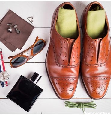 عکس کفش مردانه قهوه ای در کنار کیف پول و کراوات و ساعت مچی