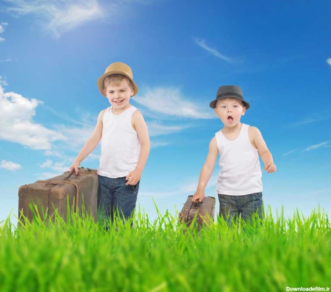 دانلود تصویر با کیفیت دو پسر با چمدان در حال قدم زدن روی چمن
