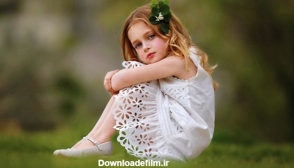 عکس دختر بچه خوشگل و زیبا با دامن سفید نشسته روی چمن