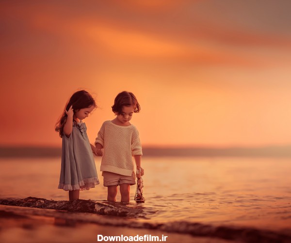 عکس بازی دختر بچه ها در کنار ساحل دریا در منظره غروب