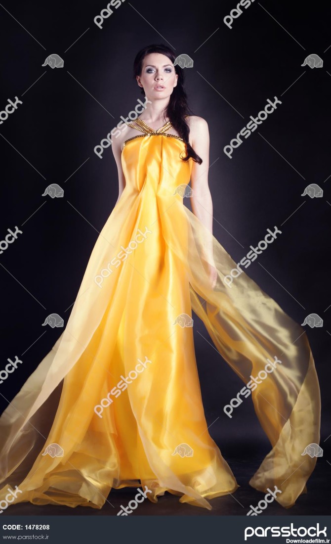دختر زیبا با تمام قد در یک لباس زرد زیبا و بیش از پس زمینه سیاه ...