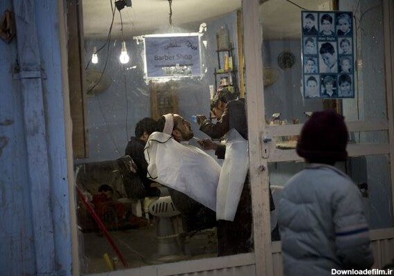 پسری به آرایشگاهی در کابل سال ۲۰۱۳ نگاه می کند که در آن ریش مردی در حال کوتاه شدن است - اسپوتنیک ایران
