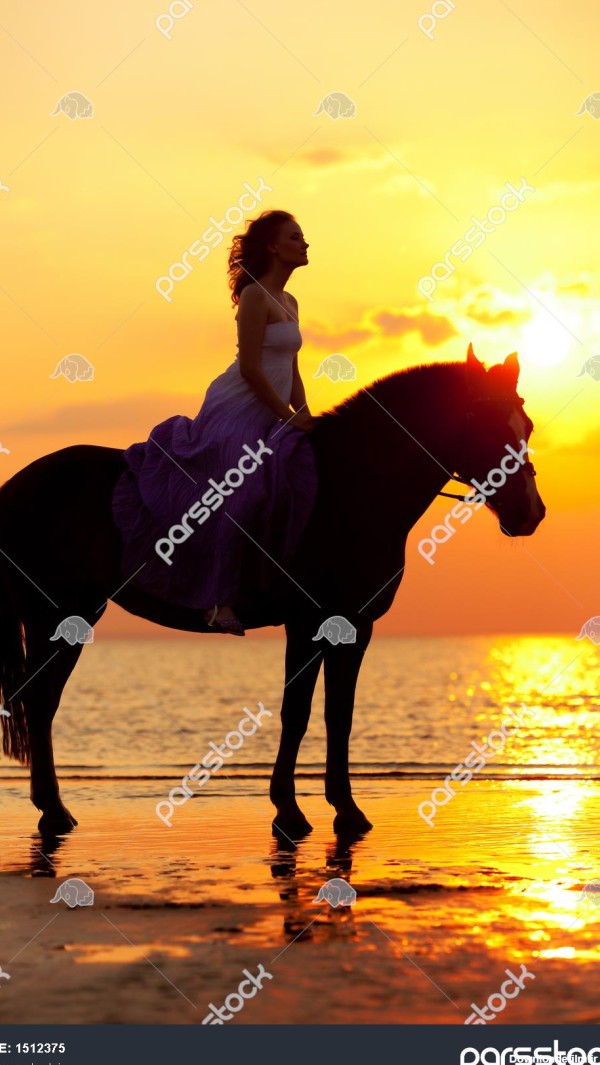 زن زیبا سوار بر اسب در غروب آفتاب در ساحل جیر جوان 1512375