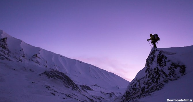 تصویر کوهنورد ایستاده بالای صخره و فصل زمستان | پیکفری
