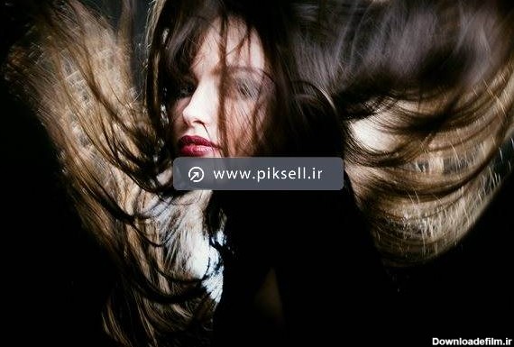 عکس با کیفیت از دختر جوان با موهای پریشان در هوا