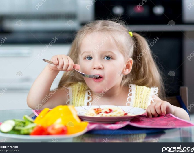 بچه در حال خوردن اسپاگتی با سبزیجات در مهد کودک یا خانه 1287631
