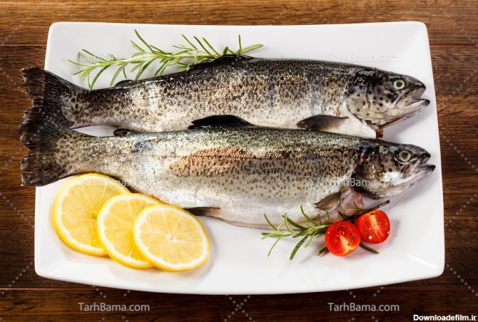 تصویر با کیفیت دو ماهی خام در بشقاب سفید با لیمو و گوجه اسلایس