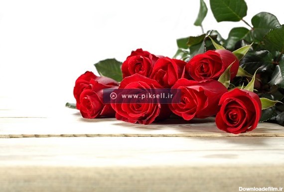 تصویر با کیفیت از دسته گلهای رز قرمز روی میز چوبی