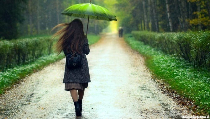 نمای هنری غم انگیز از دختر زیر باران با چتر با تم کلی سبز