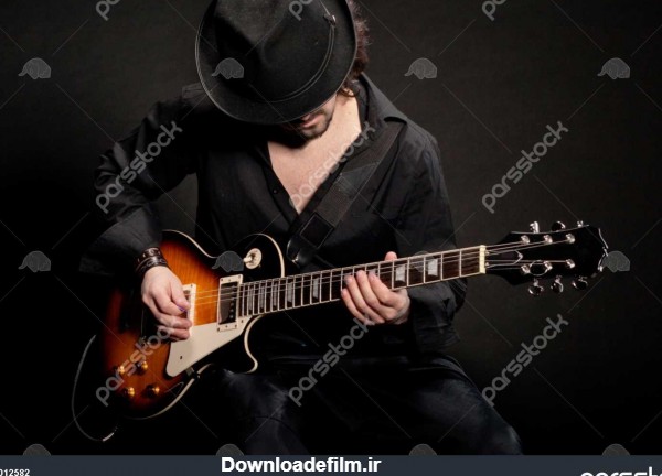 یک مرد بازی گیتار الکتریکی در لباس سیاه و سفید 1012582