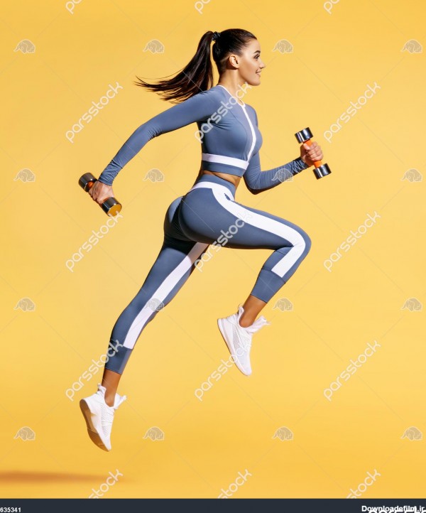 زن ورزشکار در حال پریدن با دمبل عکس زن فعال با لباس ورزشی در زمینه ...