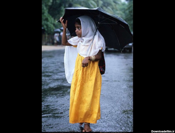 قدم زدن يك دختر بچه محجبه در زير باران با چتر