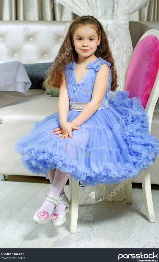 دختر فرفری کوچک در لباس آبی روی صندلی نشسته 1154131
