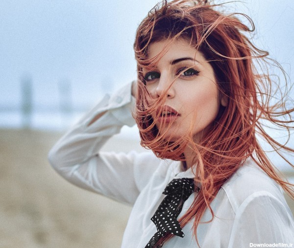 عکس زن خوشگل با موهای پریشان در کنار ساحل طوفانی