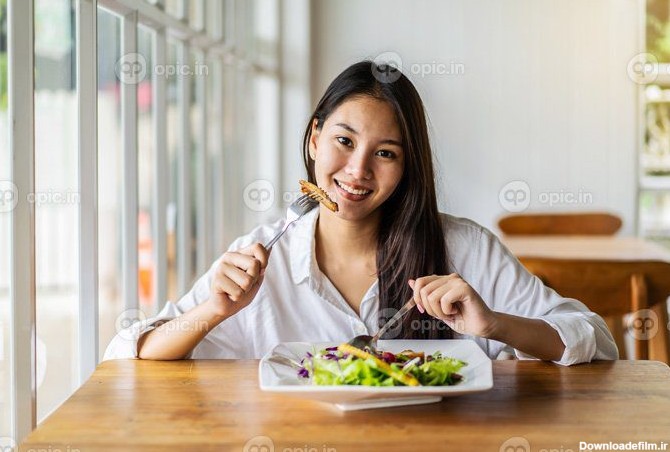 دانلود عکس پرتره زن جوان خندان آسیایی در حال غذا خوردن | اوپیک