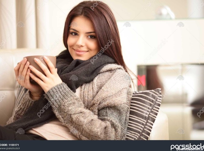 زن جوان نشسته روی مبل در پارچه دنج با فنجان قهوه 1155171