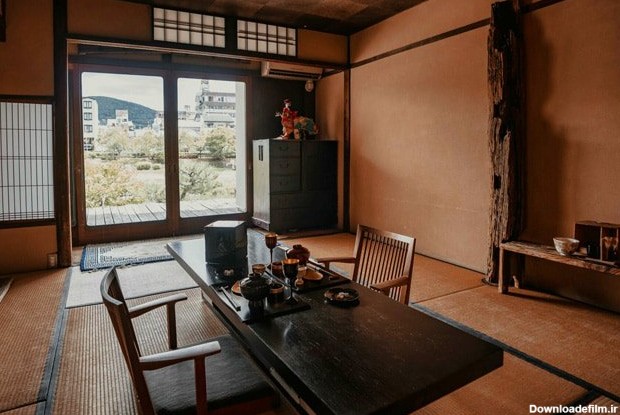 اتاقی با میز ناهارخوری مستطیل شکل قهوه ای ژاپنی مقابل درب شیشه ای رو به طبیعت