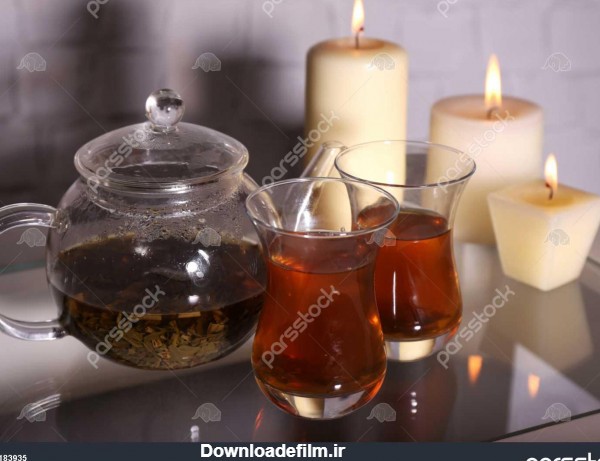 ترکیب با چای در قوری پیرکس و شمع بر روی میز در نور پس زمینه 1183935