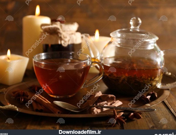 ترکیب با چای در فنجان و قوری و شمع بر روی میز در زمینه های چوبی ...