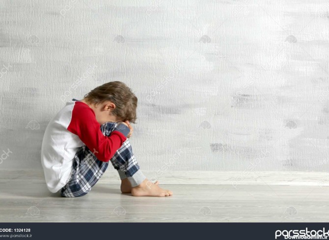 پسر کوچک غمگین در اتاق خالی روی زمین نشسته است 1324128