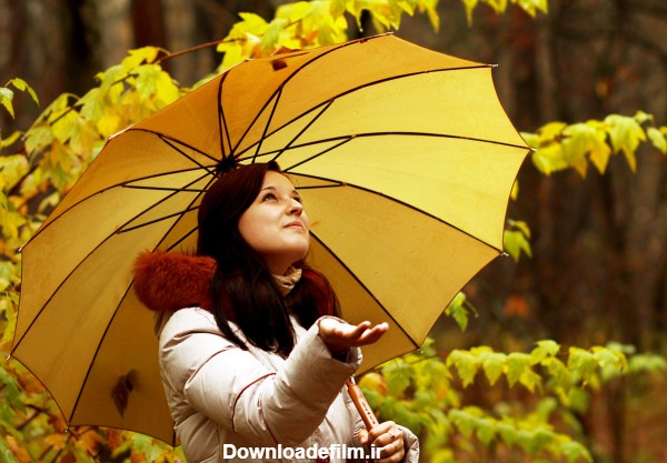 عکس دختر زیبا با چتر زیر بارش باران در فصل پاییز