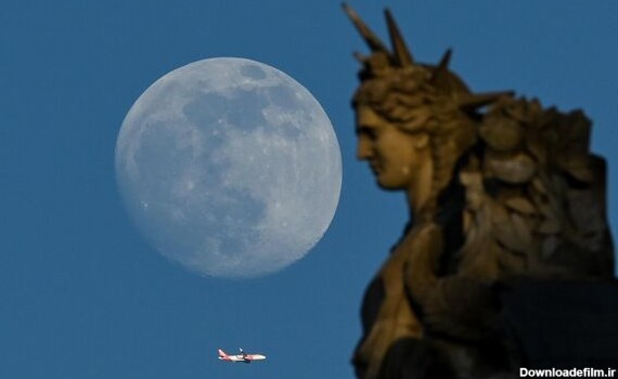 با طلوع ماه غول‌پیکر در پاریس، در 3 می 2023، یک هواپیما از کنار مجسمه لوور پرواز می‌کند. - اسپوتنیک ایران