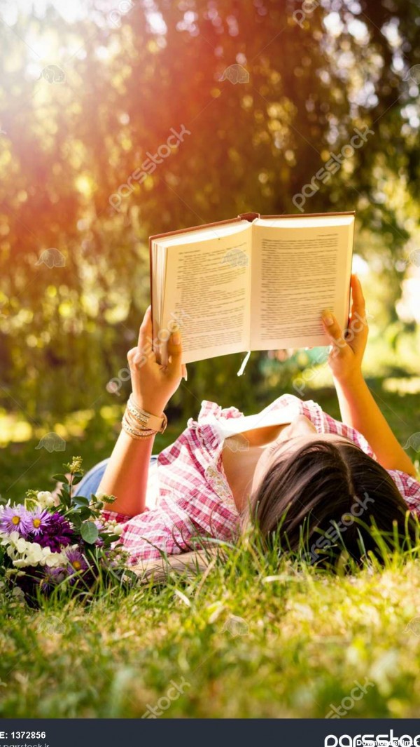 زن جوان در خواندن کتاب در پارک با گل 1372856