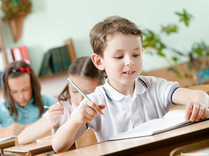 دانلود تصویر باکیفیت پسر بچه زیبا در حال مشق نوشتن در مدرسه