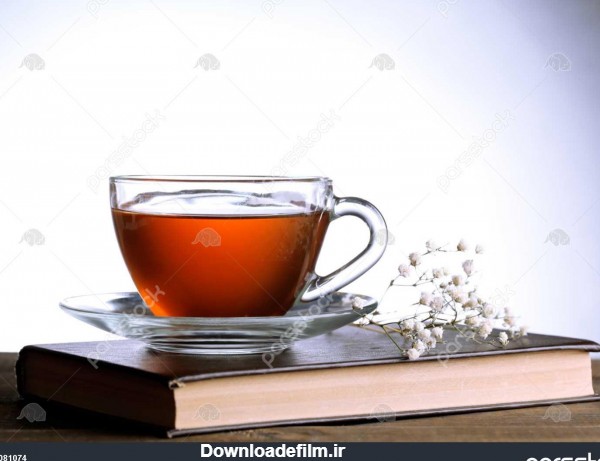 فنجان چای داغ در کتاب با گل روی میز در پس زمینه خاکستری 1081074